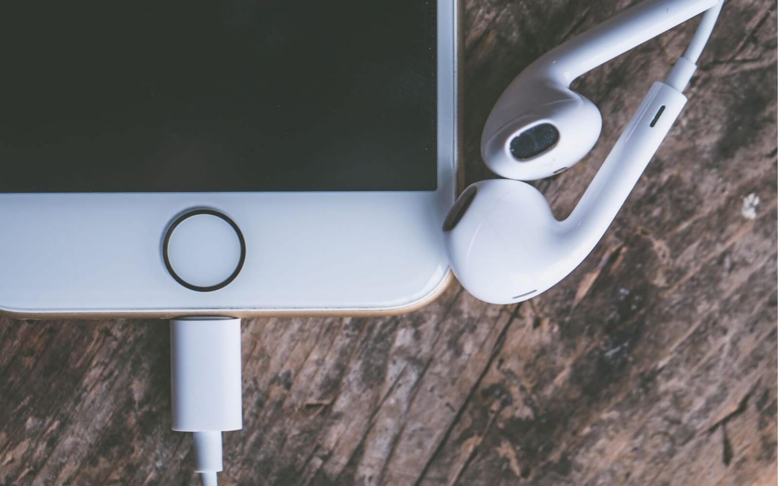 Earphones and an iPhones lying on a table.